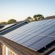 Residential rooftops with solar panels catching golden sunlight in a neighborhood setting