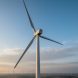 Wind turbine with rotating blades generating clean energy, with additional turbines visible in the distant background.