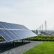 Modern solar panel array in the foreground with distant power lines and utility poles representing community electricity supply and grid infrastructure.