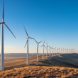 Panoramic view of wind turbines along a Wyoming ridgeline under golden hour sunlight.
